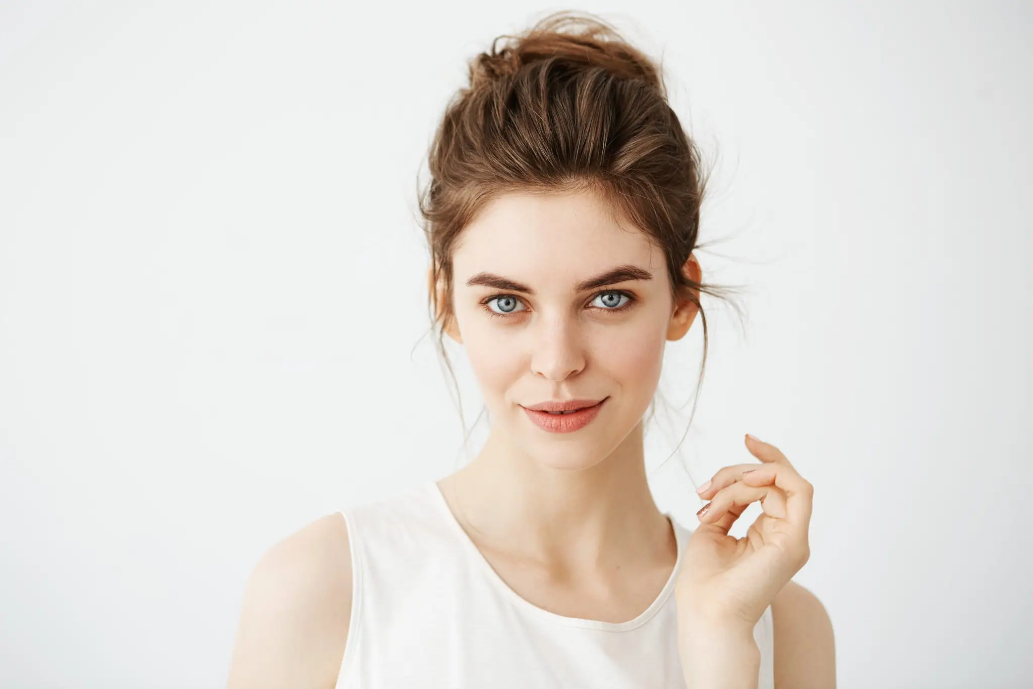 Smiling woman with her hair in a bun against a light background